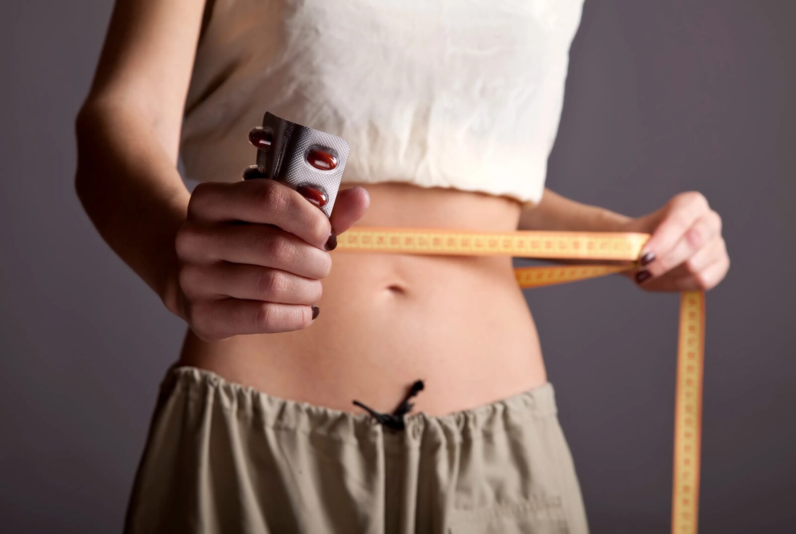 A person holding a chocolate bar in one hand and a tape measure in the other